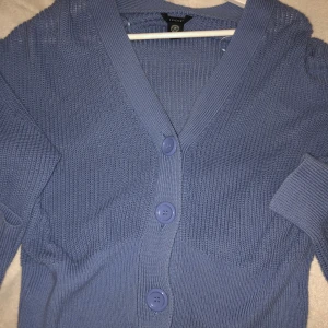 Blå stickad tröja med knappar  - Blå stickad tröja med knappar från Lindex. Köpt för några månader sedan, men bara använt en gång. Storlek m. Nypris: 600 kr 