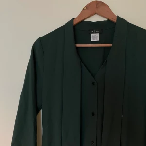 Mörkgrön jumpsuit med knytdetalj - Kostymliknande jumpsuit med knytdetalj i storlek 36, men jag skulle säga att den är mer som en 38. Färgen syns bäst på FÖRSTA bilden :)