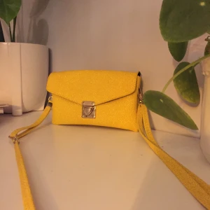 Väska - En gul väska. Den är mer guldig i färgen. 