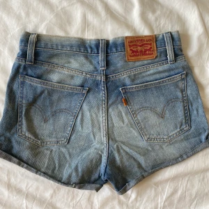 Levis shorts strl 26 - Äkta Levis shorts som sitter otroligt bra, midjehöjd strax under naveln. Gott skick, slitningen är modellen. 