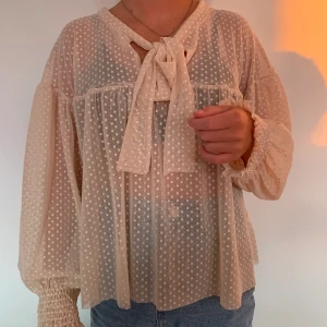 Genomskinlig blus - En ljusrosa härlig blus för sensommarns fester. Vid i modellen med en snygg roset som detalj i halsen. 🎀 Använd en gång, därmed i mycket fint skick.        Pris:150kr + frakt