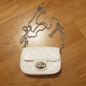 Mini handväska  - Mini handväska med söt avhackbar kedja. Väskan är ca 12cm bred och kedjan är ca 125cm. Jag tycker att det är en bra längd, men går annars att byta ut. Kommer från Attitude. Säljes för 35kr exklusive frakt (22kr). Dock ingår alltid frakt vid köp över 300kr