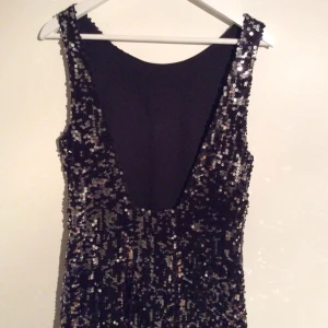 Svart/silvrig paljettklänning med djup rygg från Gina Tricot. Använd vid ett tillfälle. - Svart/silvrig paljettklänning med djup rygg från Gina Tricot. Använd vid ett tillfälle.