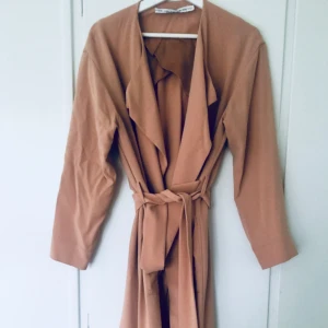  - Klassisk puderrosa trenchcoat som passar till allt! Tunt material men kan även användas under hösten med något tjockare under, relativt stor i storleken 