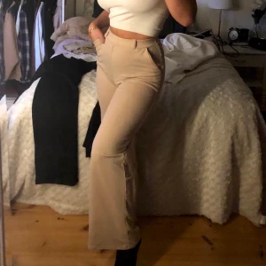 beiga kostymbyxor - frakt ingår i pris! beige-ljusrosa ”kostym”byxor, använda ca 2 gånger. köpta för 2 år sedan ungefär.  väldigt bekvämt och stretchigt material, inte som vanliga kostymbyxor. band som går att knyta till rosett i midjan ingår. 