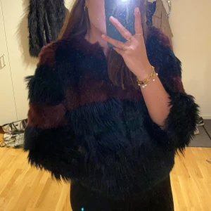 Faux Fur pälsjacka - Vinröd/svart/mörkgrön randig pälsjacka från Sisley som är köpt i Italien. Använd ett fåtal gånger, i storlek 42. Säljer pga dålig användning av den. 