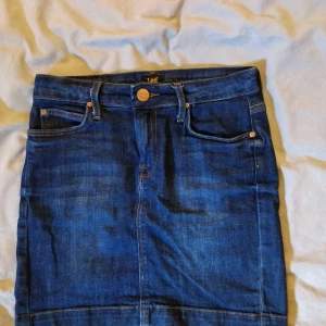 Lee jeanskjol, w24 - Jeanskjol from Lee, använd endast ett fåtal gånger. Säljer för att den pga för liten. Plaggets längd ca 38cm. Stretchigt material, kjolen sitter ganska tajt. Köpare står för frakt.