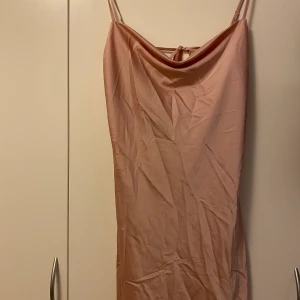 Supersnygg NELLY satinklänning - Ljusrosa satinklänning i storlek 34, men även en 36 kan ha denna. Öppen rygg och snörning där också. Smala band som man även kan justera hur man vill ha dom. Den är aldrig använd, enbart provat den. Frakt tillkommer! 
