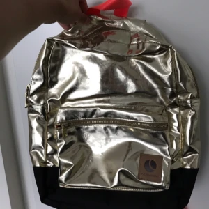  - Metallic guld ryggsäck från Björn Borg med neonorange remmar. Superläcker! Lite skavd i kanterna, men inte mycket använd.  Köparen står för eventuell frakt.