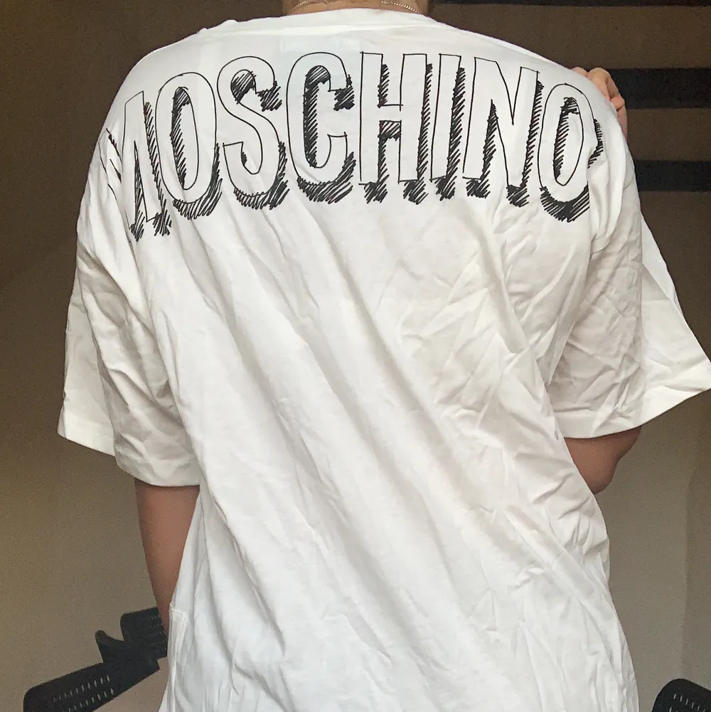 T-shirt från moschino, använd 1 gång. Coolt print fram och där bak står det moschino. Går att ha på 2 olika sätt, antingen uppknuten eller nedsläppt. . T-shirts.