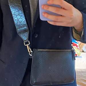 Carin Wester-väska - Fin Carin Wester-väska i nyskick. Själva väskadelen är i ormskinsimitation är och bandet är blankt med ”repor”. SÅ fin väska som tyvärr inte kommer till användning längre.