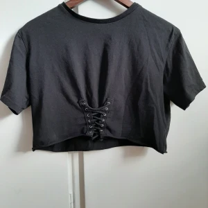 Rockig croptop  - En croptop i svart med snörning i fram. Något använd men bra kvalitet. Säljer pga den inte används. Köparen betalar för frakten