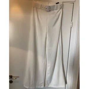 Vita kostymbyxor med vida ben - Vita kostymbyxor med vida ben och skärp i midjan. Ej genomskinliga. Aldrig använd, lapp kvar!