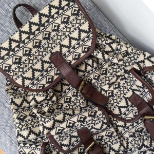 Ryggsäck (oanvänd)  - Cool och praktisk mönstrad ryggsäck. Den har 4 st fack på utsidan och 3 st fack på insidan varav ett har dragkedja. Alla yttre fack stängs med magnet. Skriv till mig vid intresse eller om du har några frågor☀️ Fraktkostnad tillkommer! 