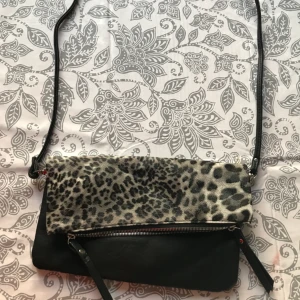  - Väska med tunnt band, svart och grå leopardmönstrad. 