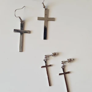  - Två par örhängen i silvrig metall med kors. Finns i Örebro men kan skickas