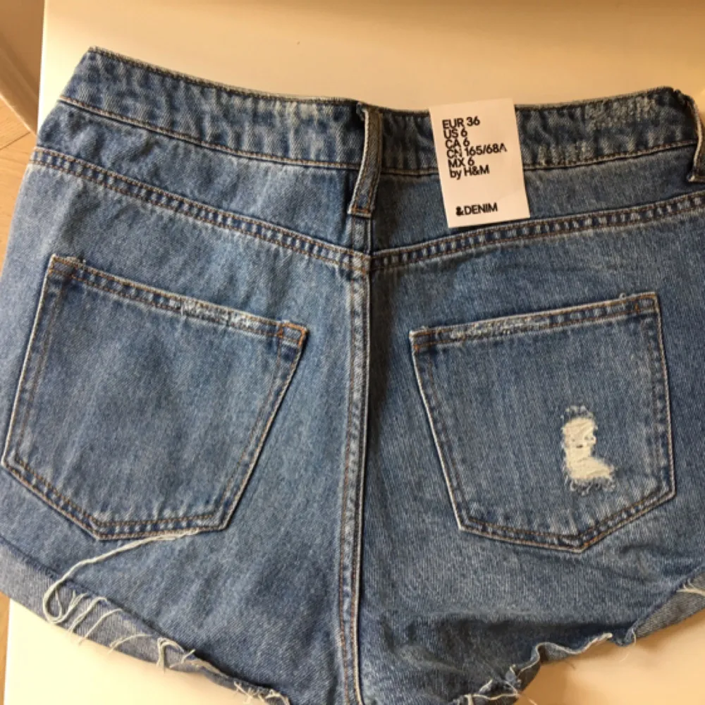 Oanvända korta jeansshorts med avklippt kant och slitage. . Shorts.