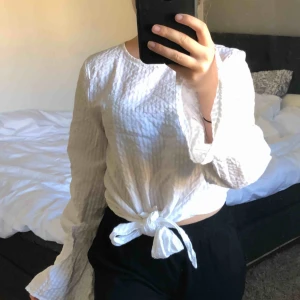  - Vit tröja med knyte där fram som gör att man kan knyta den löst eller tight beroende på vad du själv vill ha! Knappar där bak högst upp. 