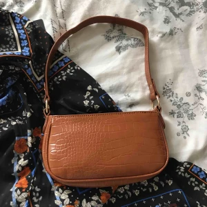  - trendig brun axelväska i nytt skick. liiiiite mörkare än vad den ser ut på bilden! 