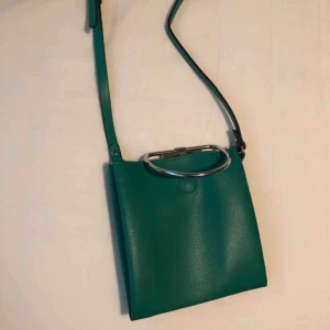  - Grön axelväska med en snygg detalj. Två fickor med knäppning🦎 Nyköpt för 250:-