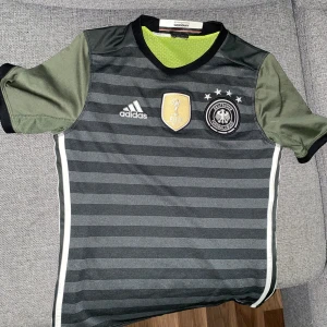 Tyskland Adidas Bortaställ EM 2016 - Säljer Tyskland feta bortaställ från 2016 som blir till en väst om man vänder den ut och in. Har endast använt den ett fåtal gånger så den är i nyskick. Säljer för att jag har växt ur den, är 176 cm lång och den är för liten för mig. Pris kan diskuteras