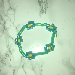 Hemmagjort  - Hemmagjort armband med blommor i färgerna blå och grön armbandet är i bra skick har ni några frågor är det bara att skriva 