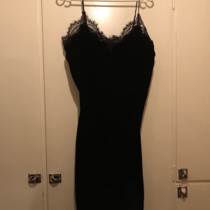 Svart klänning med spets - Svart klänning i plysch med spets upptill och nedtill. Storlek M. 