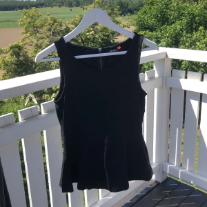 Linne - Svart linne som sitter tightare upptill och går ut nedanför midjan. Dragkedja i ryggen