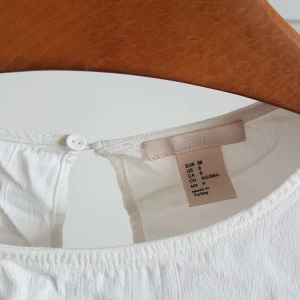 Croppad vit 3/4 blus - Jättefin vit blus. Skrynklig pga oanvänd i garderoben. Härlig textur och superfin utkörning i ryggen. Storlek 38 men passar bättre på en 36a. Tre kvarts ärm. Frakt ingår :)