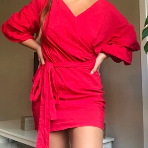 Hallonröd wrapdress - Säljer denna superfina hallonröda wrapdressen med puffärmar från Zara. Storlek L men skulle säga att den även passar M. Köparen står för frakt