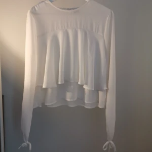 Blus med volang och knytdetalj  - Fin blus endast använd en gång. Har vanligtvis stl 36 men denna 40 passar fint, troligtvis passar den även bra på 38-40. Fin knytdetalj på ärmarna. 