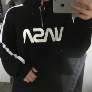 Collegetröja  - Svart collegetröja med vita ränder på ärmarna och tryckt text. Tröjan är mycket använd men fortfarande i väldigt fint skick. 60kr + frakt (tar bara swish). (fläckarna är på spegeln)