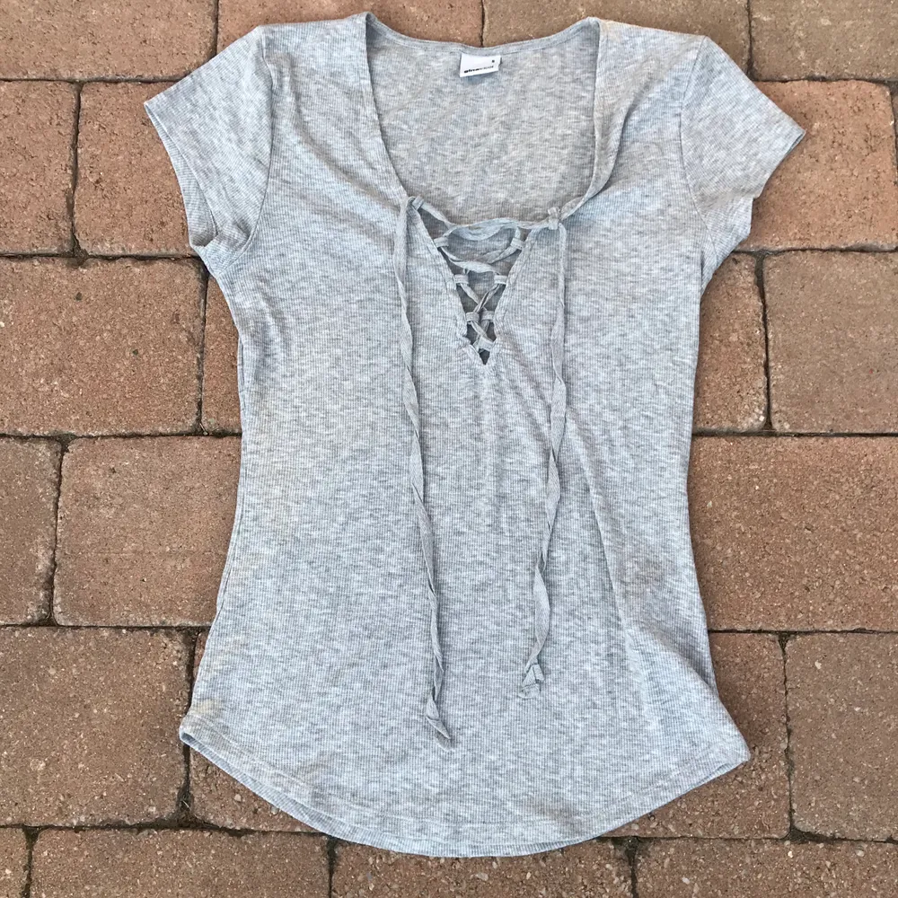 En fin grå t-shirt med snörning ifrån Gina Tricot i storlek S. Har endast använt den någon gång så den är i bra skick. (Frakten ingår i priset). T-shirts.
