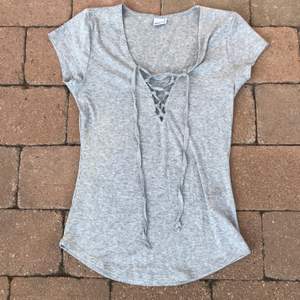 En fin grå t-shirt med snörning ifrån Gina Tricot i storlek S. Har endast använt den någon gång så den är i bra skick. (Frakten ingår i priset)