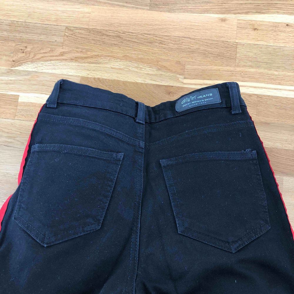 Svarta jeans med två röda streck på varje ben längs med sidorna. Högmidjade. Mom fit modell. Använd endast enstaka gång, som nya. Fint skick. Frakt tillkommer. Jeans & Byxor.