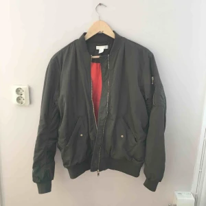  - Klassisk bomberjacka i militärgrönt. Foder i orange och tre fickor. Ett riktigt bra basplagg till garderoben!