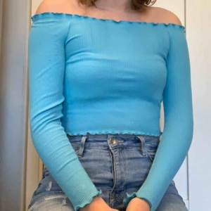 Offshoulder tröja - En jättefin ribbbad offshoulder topp i en klar turkos färg! Perfekt sommar topp! Köpt på Gina och knappt använd, säljer pga för liten för mig. 50kr+45kr frakt. Säljer även jeansen på bilden!