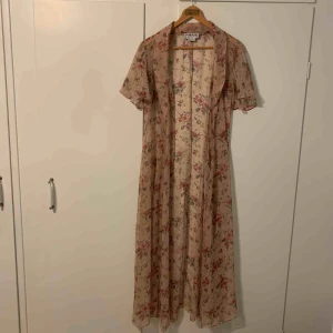  - Blommig lång kaftan i skirt tyg. Kan knytas omlott som klänning, saknas dock midjeband. 