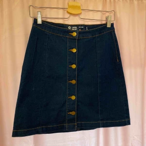 Mörk jeanskjol - Använd ett fåtal gånger men som gått som ny. Stretchigt jeans material med knappar framtill