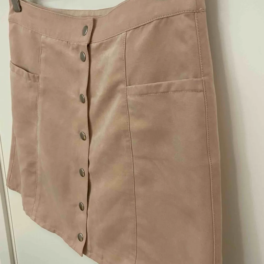 Gammalrosa kjol med knappar som öppning. Finns 2 främre fickor. Lent o mjukt tyg, använd ett fåtal gånger. . Kjolar.