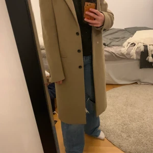 Beige kappa i strl S - Säljer min sååå fina kappa!! Den är i mycket bra skick då den är väldigt sparsamt använd. Den har knappar och är varm nu till hösten och vintern