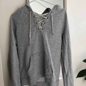  - En grå hoodie med snörning framtill. Nyskick, utan fläckar och missfärgning. Frakt kan diskuteras.  