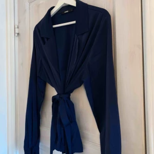  - Jättefin blus i silkes material marinblå med knappar i armarna och bälte i midjan!  Du som kund står för frakten :)