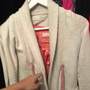  - Beige stickad kofta, rosa knytning fram. Använd fåtal gånger. 