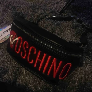  - Från HM x Moschino kollektion. Midjeväska i läderimitation, storlek 8x14x30cm. Helt nytt, kan mötas upp vid t-centralen eller Odenplan. Kan skicka via post, 60kr på frakt med spårbar