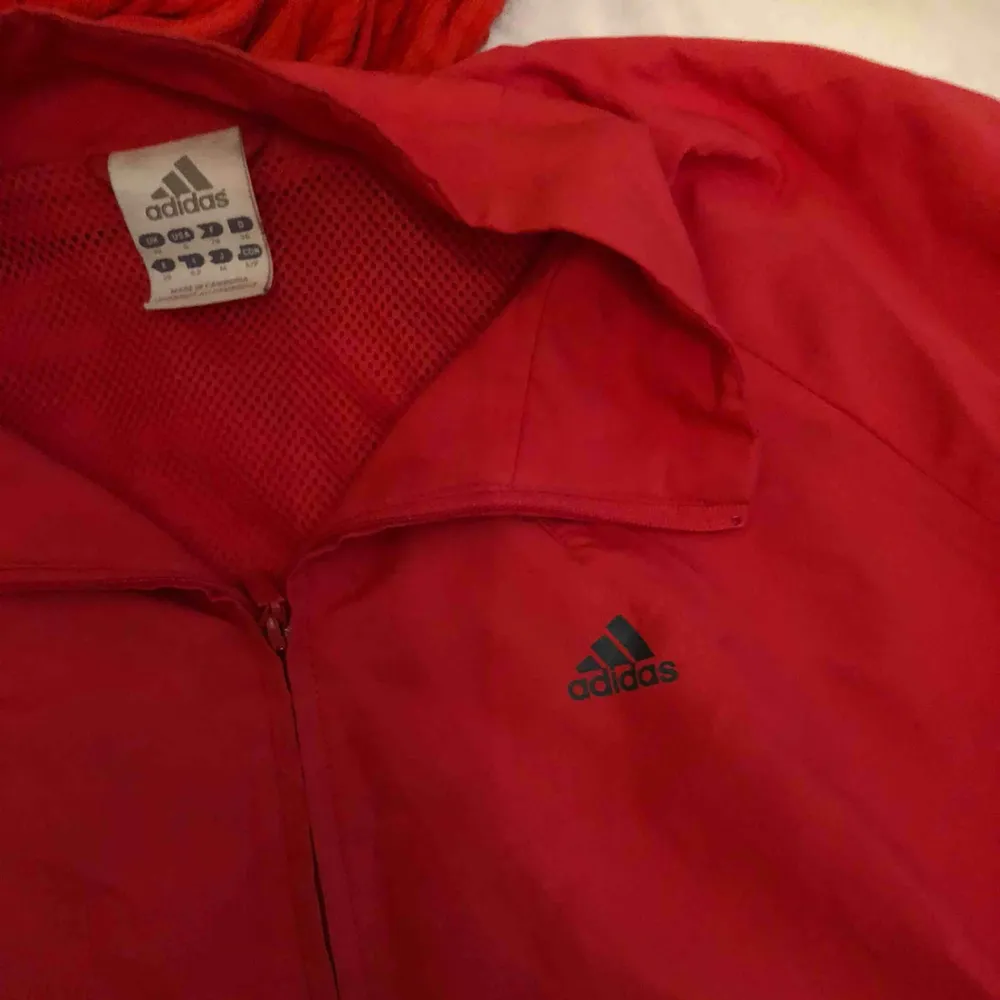 Adidas jacka i rött. En fläck på framsidan av jackan annars i bra skick. Frakt ingår. Jackor.