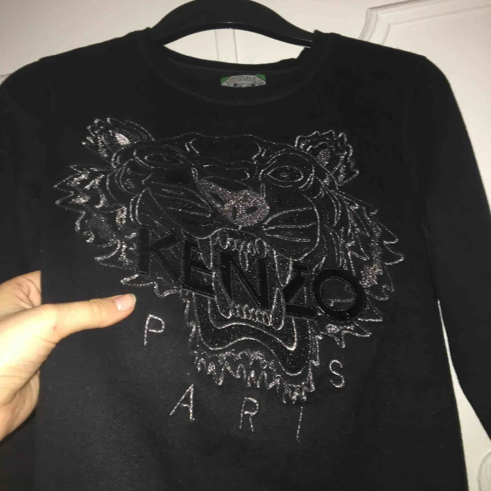 Svart Kenzo sweatshirt med silver detaljer. Ganska liten i storleken, funkar definitivt som en XS. Inga defekter men den är väl använd! Priset kan diskuteras och jag kan mötas upp i Stockholm💗. Hoodies.