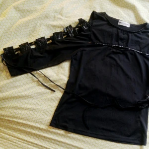  - Svart top i stretchigt material med lackdetaljer och snörning i ärmarna.
Inköpt på CUM i Stockholm,  använd ett fåtal gånger. Nyskick. 

Storlek S eller möjligen M pga stretch-tyg. 
Hämtas enl. överenskommelse eller skickas mot frakt i hela Sverige. 