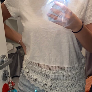 Vit t-shirt  - En vit tröja med spets löngst ner, den är ifrån Vero Moda och är i storlek S. 