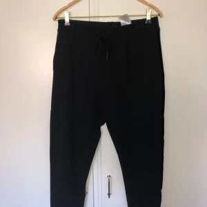 Kostymbyxor strl L - Super sköna kostymbyxor i stretchigt bomullsmaterial med snygg sammetsdetalj längst sidan av benet.